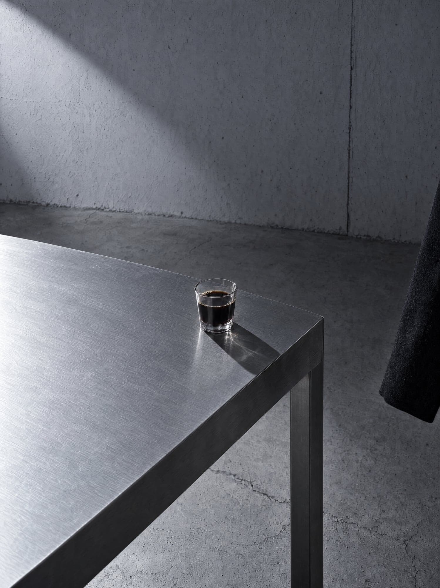 A glass of black coffee on a steel table
