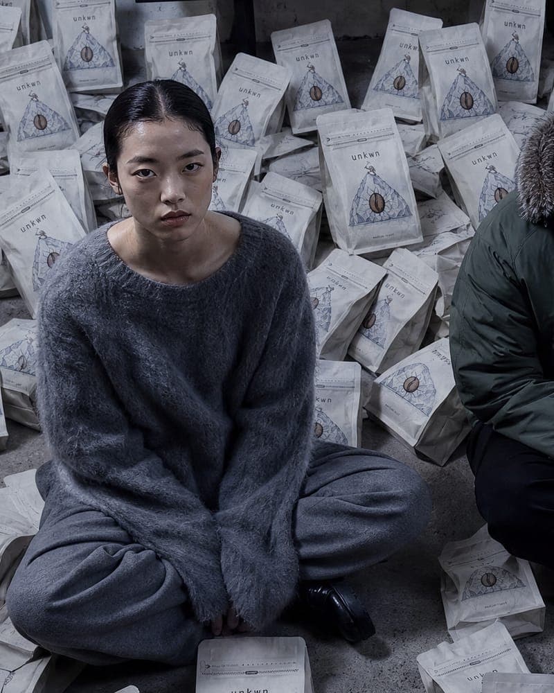 Seated figure in grey knit, campaign still